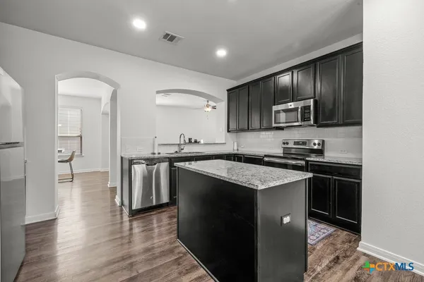 a kitchen with stainless steel appliances granite countertop a stove a sink and a microwave