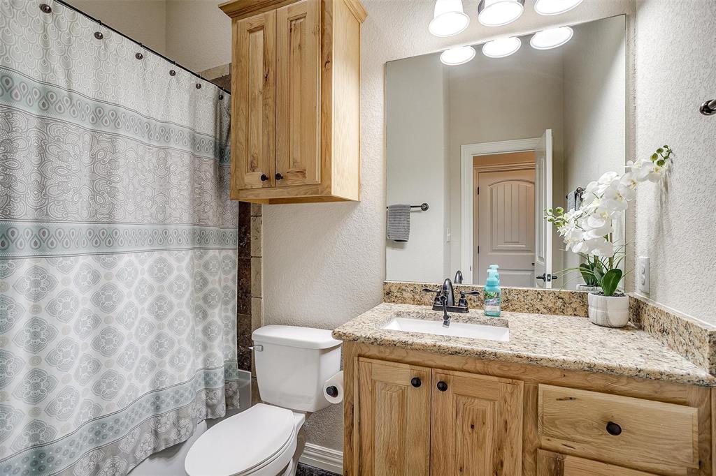505 N Avenue East Springtown, TX 76082 - Photo 21 of 27 a bathroom with a granite countertop sink a toilet and a mirror