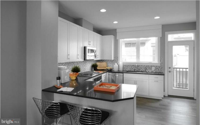 6680 Eames Way Bethesda, MD 20817 - Photo 7 of 19 a kitchen with a sink dishwasher a stove and a dining table with wooden floor