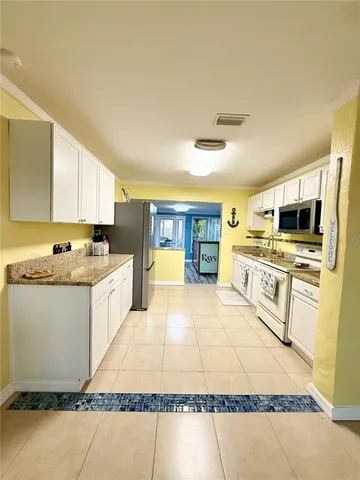 a large white kitchen with stainless steel appliances granite countertop a stove and a sink