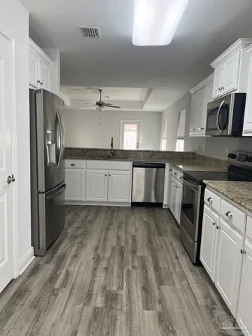 an empty room with wooden floor chandelier and windows