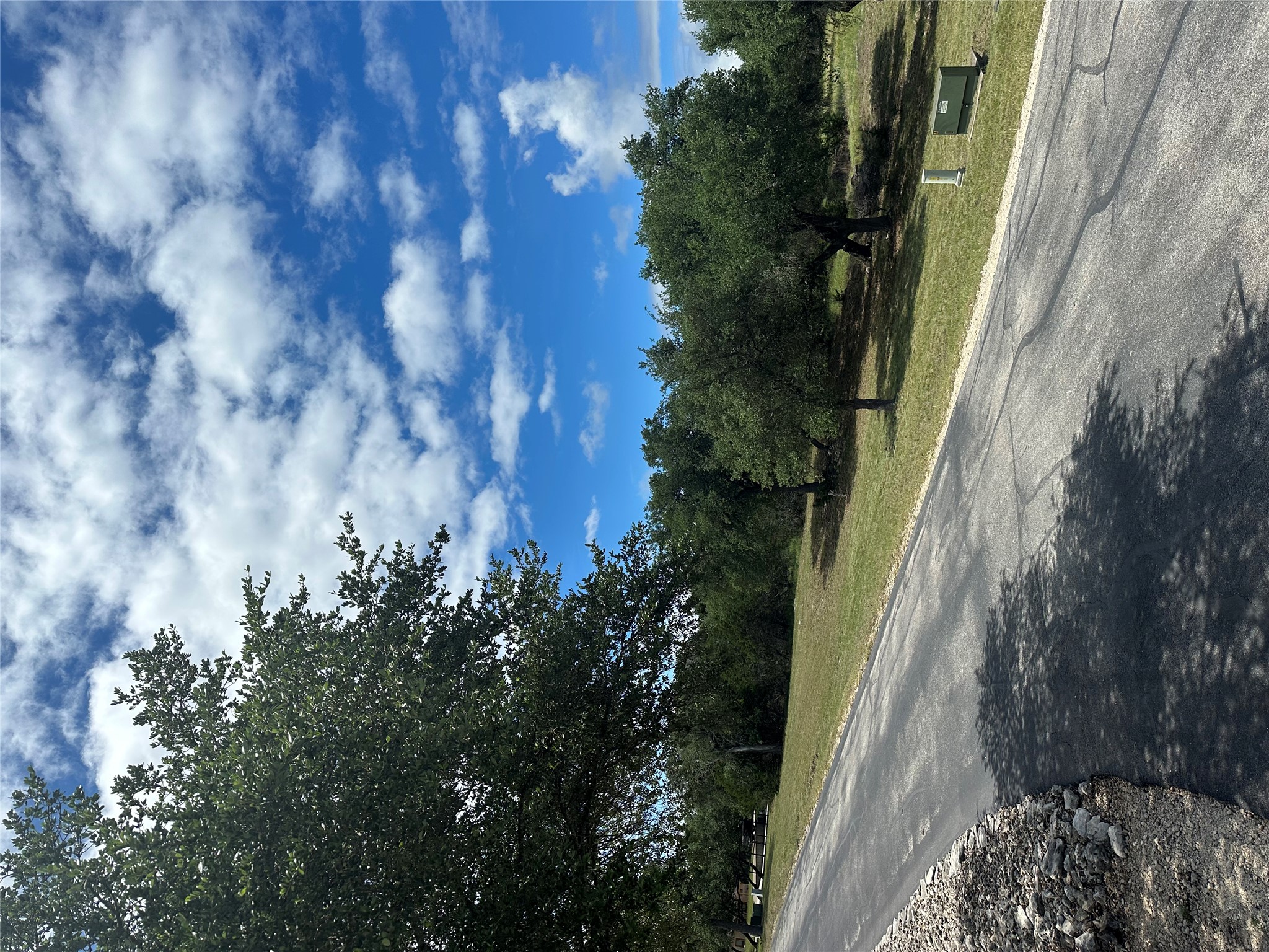 0 Lantana Gold Spring Branch, TX 78070 - Photo 8 of 15 A clear blue sky with scattered clouds hovers over a verdant landscape and an asphalt road.