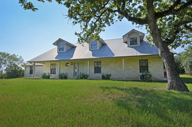 a view of a white house with a big yard and large trees