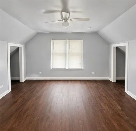 an empty room with wooden floor chandelier and windows