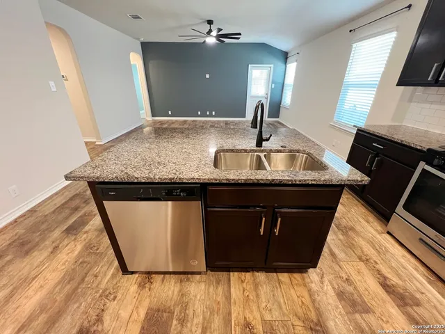a kitchen with granite countertop a sink dishwasher and a stove with wooden floor