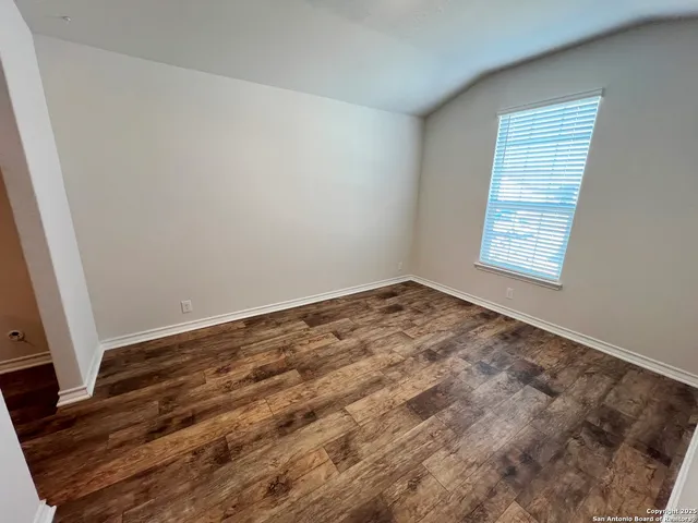 an empty room with wooden floor and window