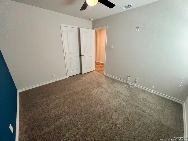 an empty room with chandelier fan and windows
