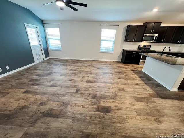 a view of kitchen and empty room with wooden floor