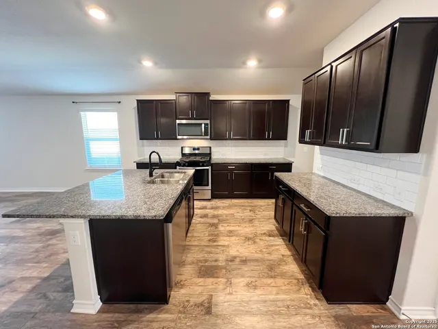 a large kitchen with granite countertop a sink and a stove top oven