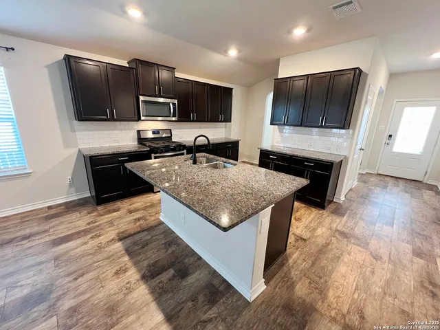 a kitchen with stainless steel appliances granite countertop a stove a sink and a microwave