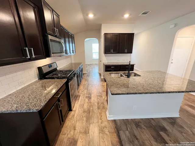 a kitchen with stainless steel appliances granite countertop a stove a sink and a microwave