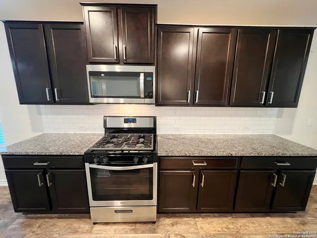 a kitchen with granite countertop stainless steel appliances and wooden cabinets