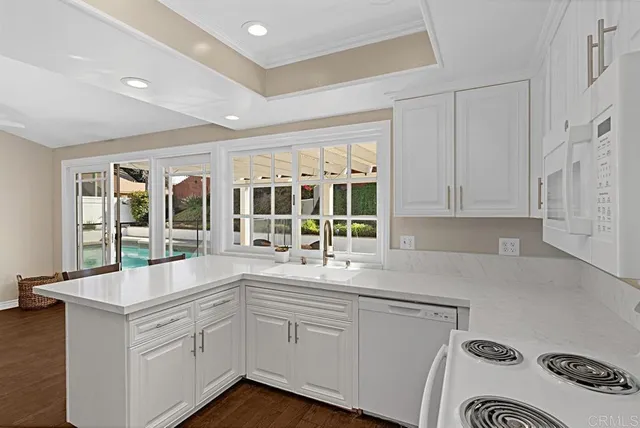 a open kitchen with granite countertop a sink and white cabinets