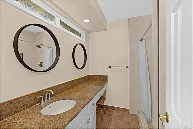 a bathroom with a granite countertop sink and a mirror