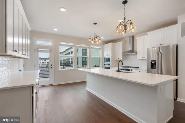 a large kitchen with stainless steel appliances a large counter top a sink a stove and a refrigerator