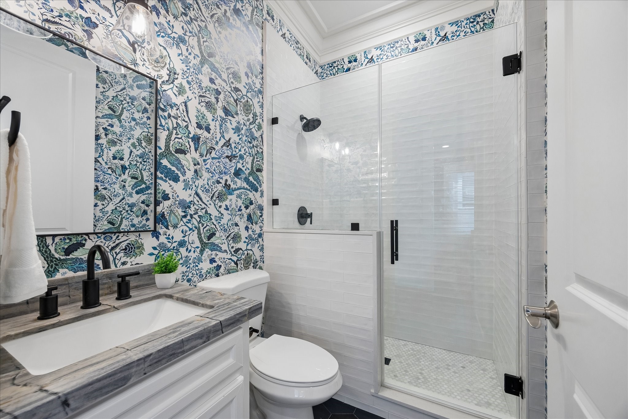 621 West 15th Street Houston, TX 77008 - Photo 6 of 37 A magazine-worthy full bath downstairs showcasing statement wallpaper, an Ijen Blue quartzite countertop, and timeless white tile finishes.