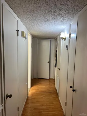 a view of a hallway with wooden floor and a bathroom