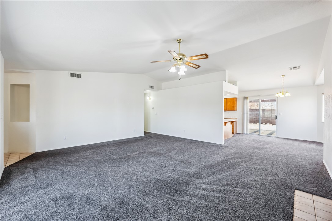 2524 South Ridge Avenue Bullhead City, AZ 86429 - Photo 15 of 64 Unfurnished living room with light colored carpet, lofted ceiling, ceiling fan, a chandelier, and baseboards
