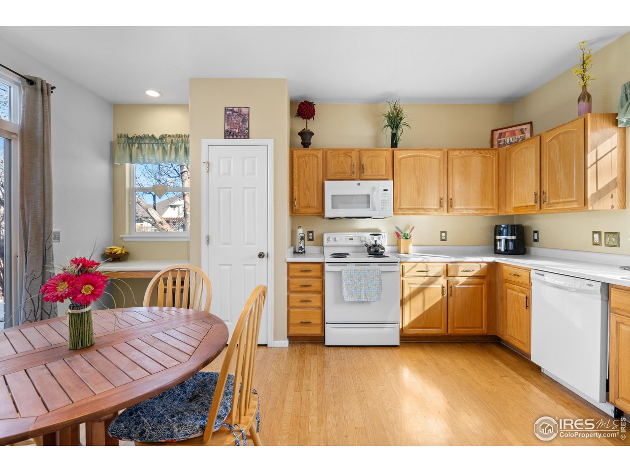 10351 Cook Way Thornton, CO 80229 - Photo 27 of 30 a kitchen with stainless steel appliances kitchen island granite countertop a refrigerator a sink dishwasher a dining table and chairs with wooden floor