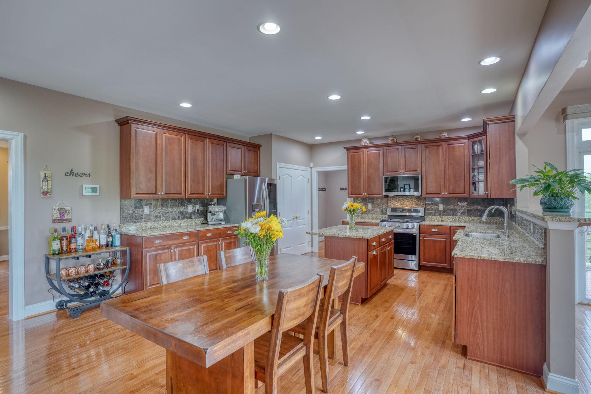 213 Loft Street Townsend, DE 19734 - Photo 35 of 76 a kitchen with stainless steel appliances kitchen island granite countertop a refrigerator a stove a sink a dining table and chairs with wooden floor