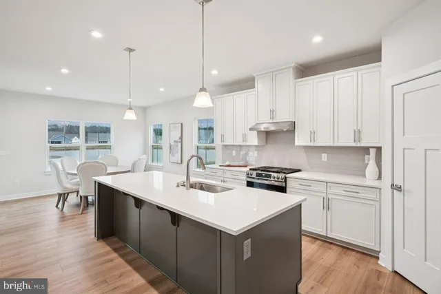 a kitchen with a sink stove and white cabinets with wooden floor