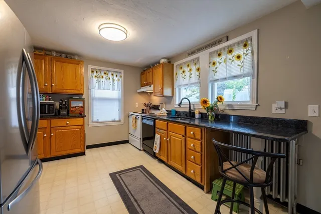 a kitchen with stainless steel appliances granite countertop wooden cabinets a stove a sink and a refrigerator