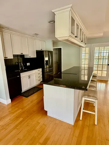 a living room with stainless steel appliances wooden floors and living room view