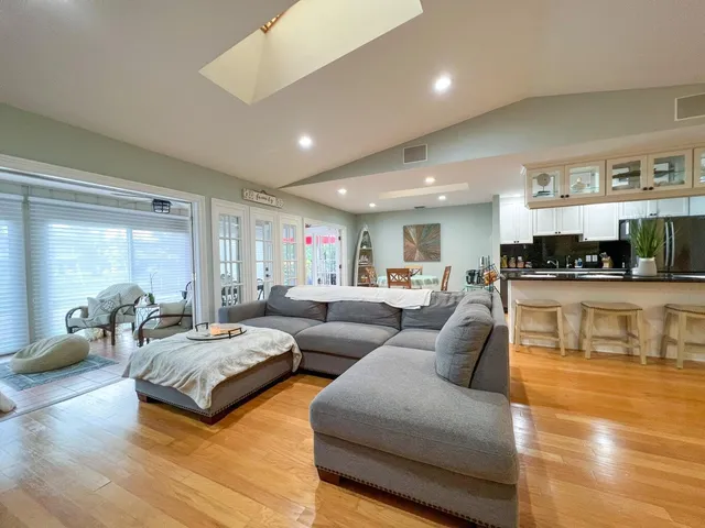 a living room with couches and kitchen view with wooden floor