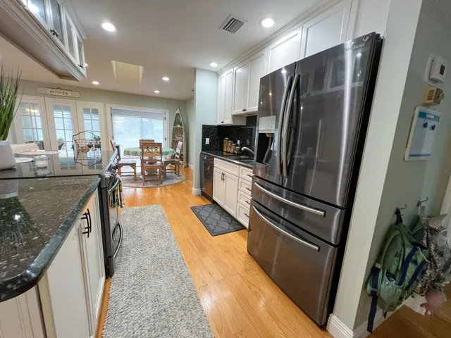 a kitchen with stainless steel appliances granite countertop a refrigerator a sink a stove and a refrigerator