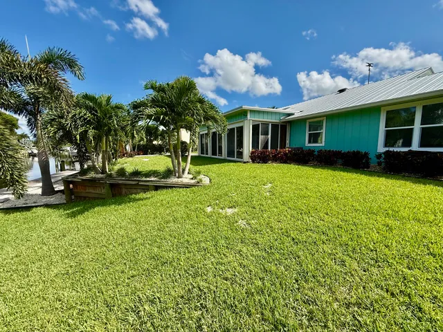 a view of a house with a big yard potted plants and large tree