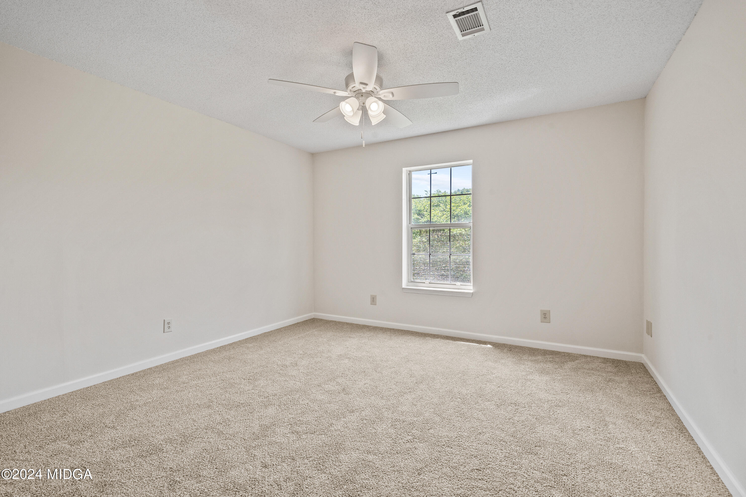 246 Langston Road Perry, GA 31069 - Photo 30 of 37 an empty room with a chandelier fan and windows