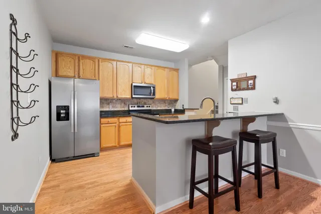 a kitchen with stainless steel appliances granite countertop a stove a sink refrigerator and a refrigerator with wooden floor