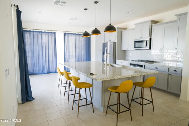 a kitchen with stainless steel appliances kitchen island granite countertop a table chairs and a refrigerator