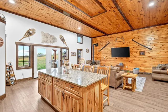 a living room with stainless steel appliances kitchen island granite countertop a sink and a wooden floors
