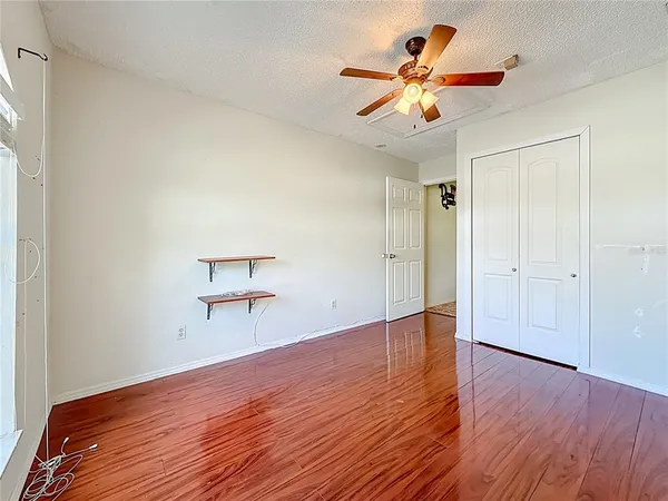 an empty room with wooden floor and fan