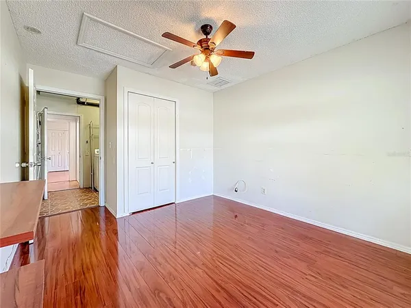 an empty room with wooden floor and ceiling fan