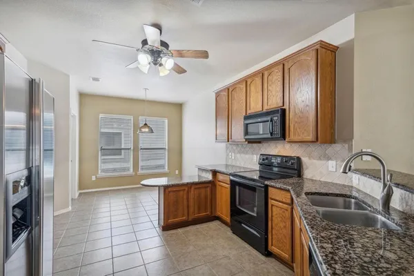 a kitchen with granite countertop a stove sink and cabinets