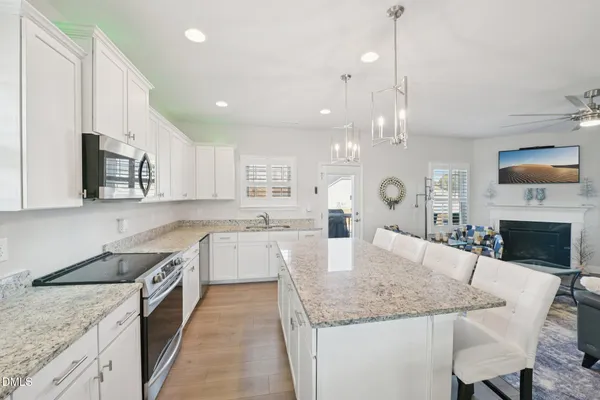 a large kitchen with granite countertop a sink a counter top space appliances and cabinets