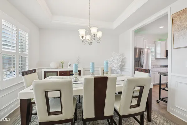 a view of a dining room with furniture a chandelier and large windows