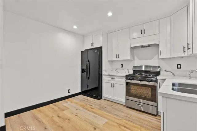 a kitchen with stainless steel appliances granite countertop a stove a refrigerator and a white cabinets