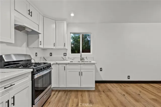 a kitchen with granite countertop a stove a sink and dishwasher with white cabinets