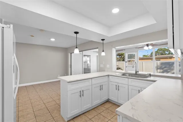 a large white kitchen with a sink window and cabinets