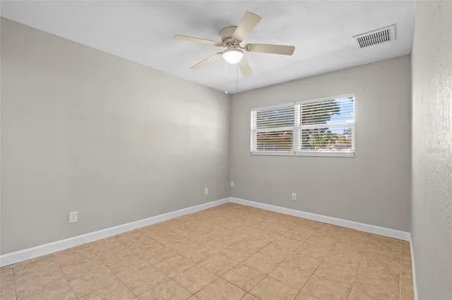 an empty room with a chandelier fan and windows