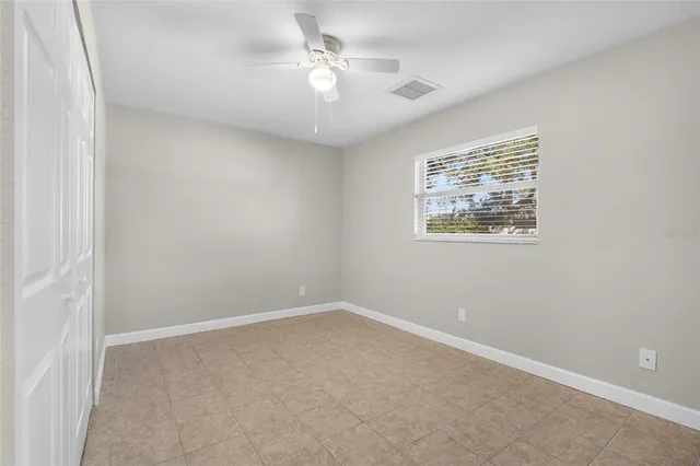 an empty room with a window and a ceiling fan