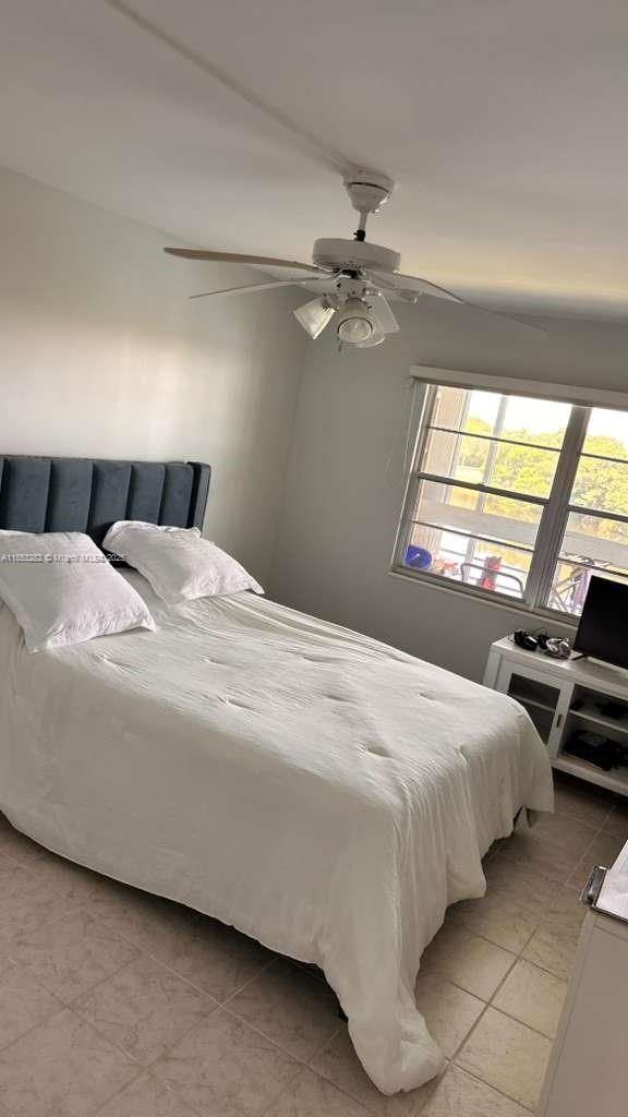 4050 Ainslie Drive, Unit 4050 Boca Raton, FL 33434 - Photo 9 of 17 a bedroom with a bed a ceiling fan and a large window