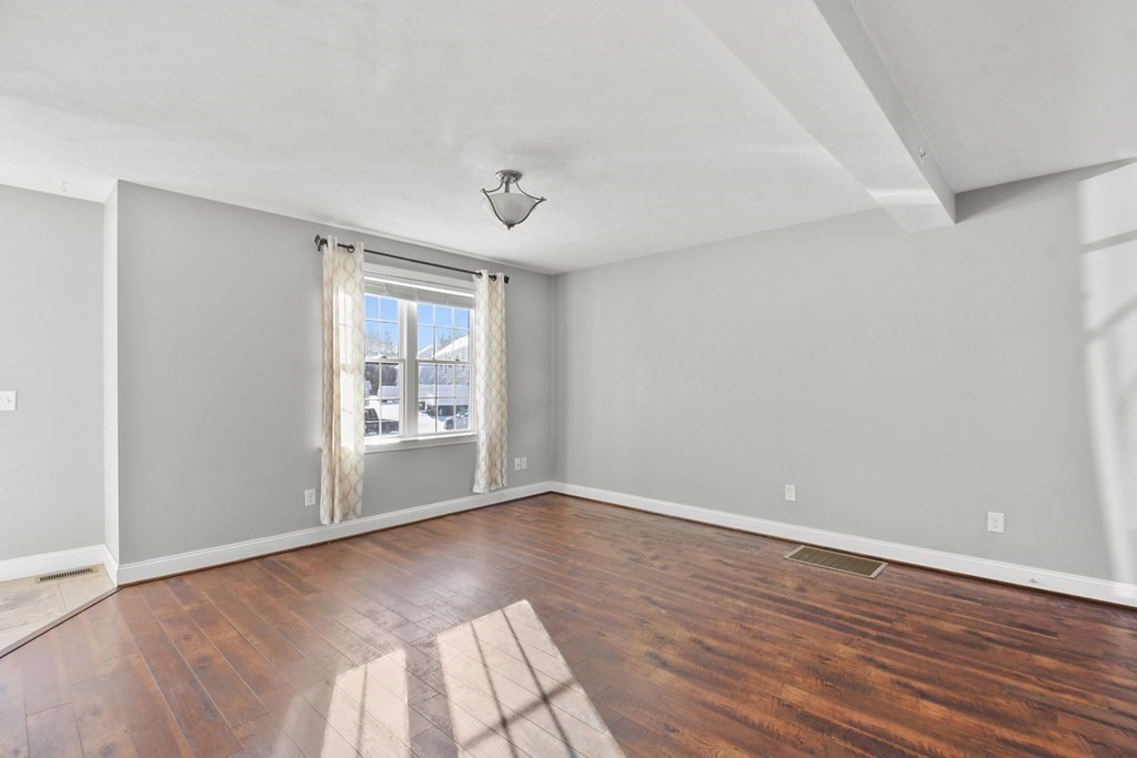 211 Barre Paxton Road, Unit 2 Rutland, MA 01543 - Photo 6 of 30 a view of an empty room with wooden floor and a window