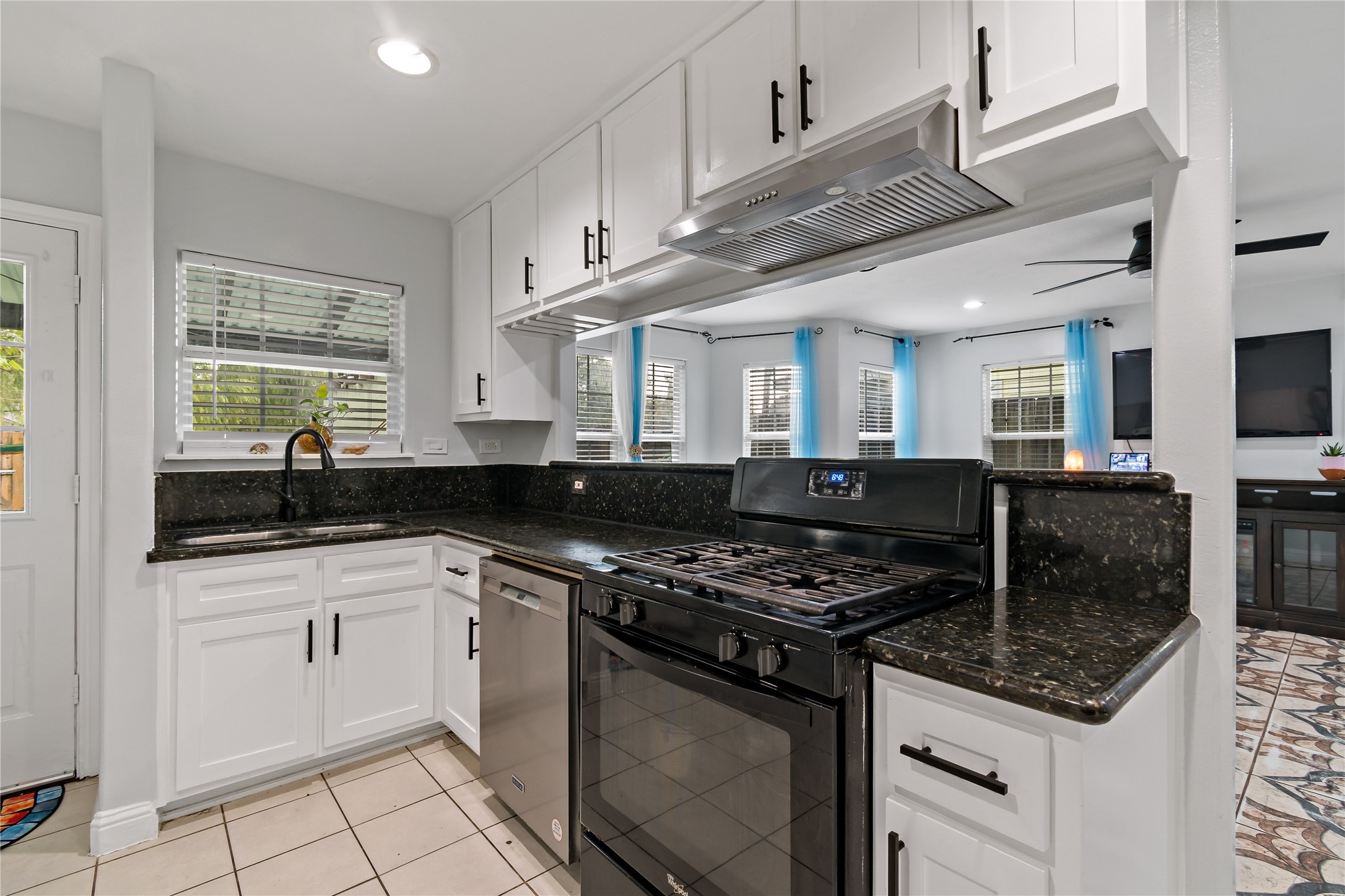 507 Firnat Street Houston, TX 77022 - Photo 6 of 22 a kitchen with granite countertop a sink a stove cabinets and black appliances