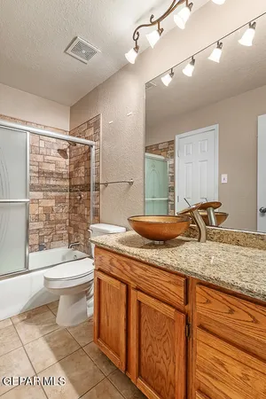 a bathroom with a granite countertop sink a toilet a mirror and shower