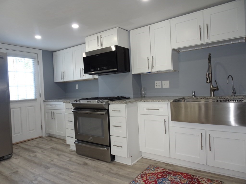 416 Crescent Avenue Chelsea, MA 02150 - Photo 5 of 21 a kitchen with white cabinets stainless steel appliances and sink