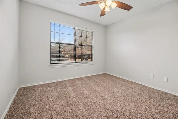 an empty room with a chandelier fan and windows